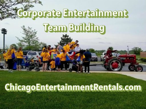 Group of people in blue and yellow shirts participating in a team-building event outdoors.