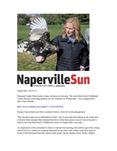 A woman holds a hawk outdoors, smiling as she interacts with the bird.